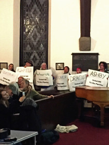 People encircle the sanctuary, holding signs that represent all the towns that have voted against the pipeline